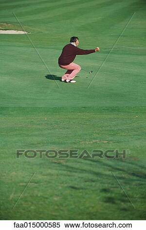 Golfer crouching on green, holding out fist View Large Photo Image Stock Photography - Golfer crouching on green, holding out fist. Fotosearch