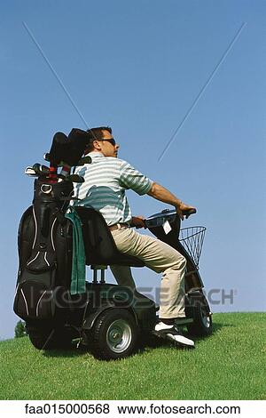 Stock Photo - Golfer driving electric golf caddy. Fotosearch