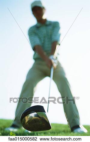Golfer holding golf club, focus on club in foreground, low angle view View Large Photo Image Stock Image - Golfer holding golf club, focus on club in foreground, low angle view. Fotosearch