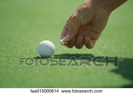 Golfer placing golf ball marker on turf, close-up of hand View Large Photo Image Picture - Golfer placing golf ball marker on turf, close-up of hand. Fotosearch
