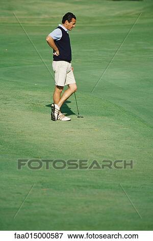 Golfer standing on green, hand on hip and ankles crossed View Large Photo Image Stock Photo - Golfer standing on green, hand on hip and ankles crossed. Fotosearch