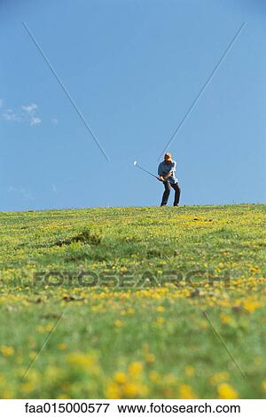Stock Photo - Golfer swinging, wildflowers in foreground. Fotosearch