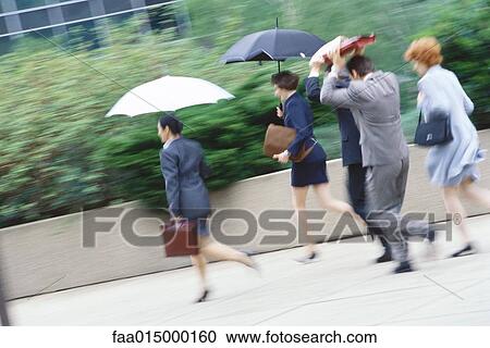 Group of business executives hurrying through rain View Large Photo Image Stock Image - Group of business executives hurrying through rain. Fotosearch