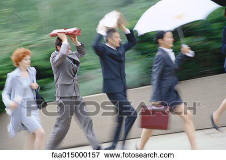 Group of business executives hurrying through rain View Large Photo Image Stock Photo - Group of business executives hurrying through rain. Fotosearch