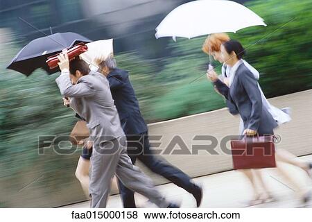 Group of business executives hurrying through rain View Large Photo Image Stock Photo - Group of business executives hurrying through rain. Fotosearch