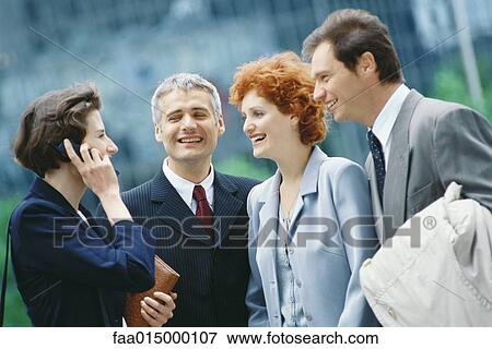 Stock Photo - Group of business executives, one woman using cell phone. Fotosearch