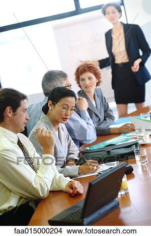 Group of businesspeople sitting around conference table during presentation View Large Photo Image Picture - Group of businesspeople sitting around conference table during presentation. Fotosearch