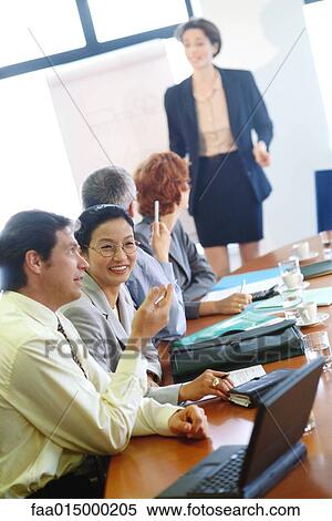 Group of businesspeople sitting around conference table during presentation View Large Photo Image Stock Photography - Group of businesspeople sitting around conference table during presentation. Fotosearch