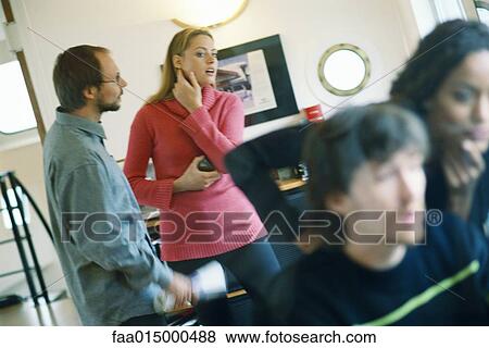 Man and woman speaking, woman looking at colleagues in foreground View Large Photo Image Stock Photo - Man and woman speaking, woman looking at colleagues in foreground. Fotosearch