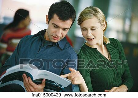 Man holding brochure, woman looking over his shoulder, pointing to page View Large Photo Image Stock Photo - Man holding brochure, woman looking over his shoulder, pointing to page. Fotosearch
