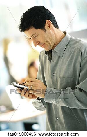 Stock Photograph - Man using electronic organizer, side view. Fotosearch