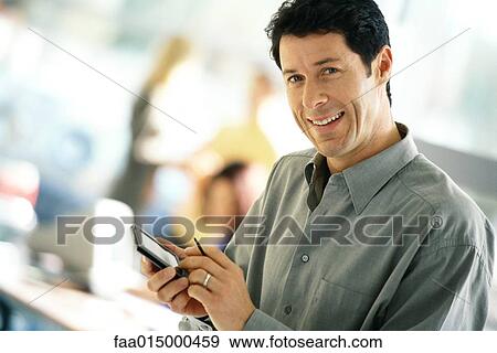 Man using electronic organizer, smiling at camera View Large Photo Image Stock Photo - Man using electronic organizer, smiling at camera. Fotosearch