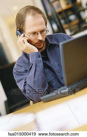 Man using laptop and cell phone View Large Photo Image Stock Photo - Man using laptop and cell phone. Fotosearch