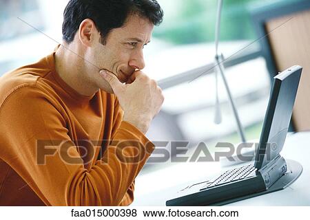 Man using laptop, hand over mouth, smiling View Large Photo Image Stock Photo - Man using laptop, hand over mouth, smiling. Fotosearch