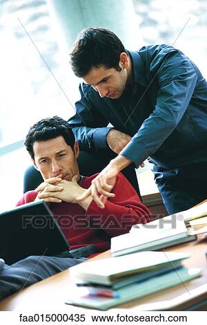 Man using laptop, second man leaning over shoulder, pointing at screen View Large Photo Image Stock Photography - Man using laptop, second man leaning over shoulder, pointing at screen. Fotosearch