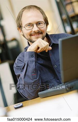 Man using laptop, smiling at camera View Large Photo Image Picture - Man using laptop, smiling at camera. Fotosearch