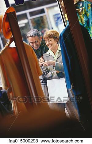 Stock Photo - Mature couple looking through shop window, laughing. Fotosearch
