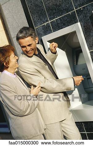 Mature couple standing at ATM machine View Large Photo Image Stock Image - Mature couple standing at ATM machine. Fotosearch