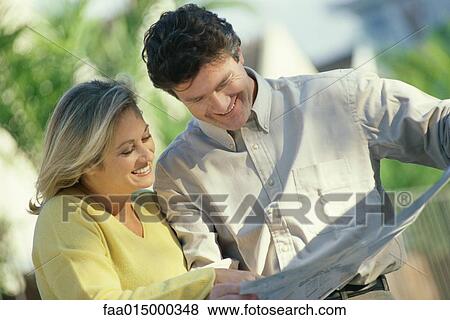 Mature couple standing outdoors, studying map View Large Photo Image Stock Photo - Mature couple standing outdoors, studying map. Fotosearch