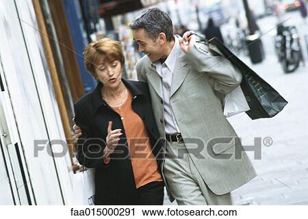 Mature couple walking on city sidewalk View Large Photo Image Stock Image - Mature couple walking on city sidewalk. Fotosearch