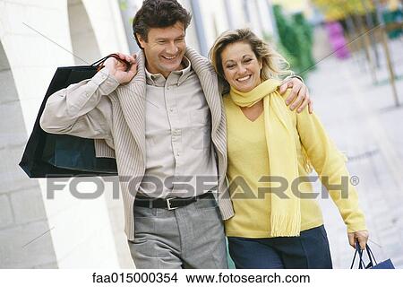 Mature couple walking with shopping bags View Large Photo Image Picture - Mature couple walking with shopping bags. Fotosearch
