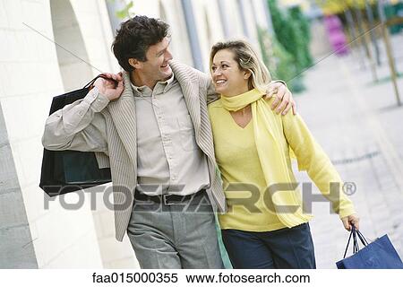 Mature couple walking with shopping bags, smiling at each other View Large Photo Image Stock Photography - Mature couple walking with shopping bags, smiling at each other. Fotosearch