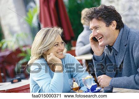 Stock Image - Middle aged couple sitting at sidewalk cafe. Fotosearch