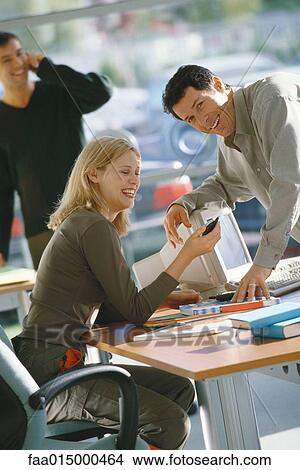 Office scene, man leaning toward female colleague, laughing View Large Photo Image Picture - Office scene, man leaning toward female colleague, laughing. Fotosearch