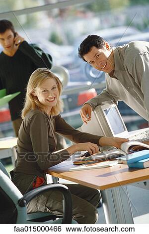 Office scene, man leaning toward female colleague, both smiling at camera View Large Photo Image Stock Photograph - Office scene, man leaning toward female colleague, both smiling at camera. Fotosearch