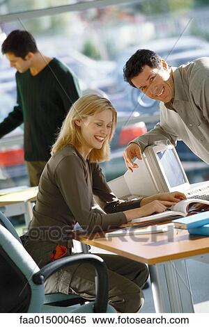Office scene, man leaning toward female colleague, laughing View Large Photo Image Stock Photography - Office scene, man leaning toward female colleague, laughing. Fotosearch