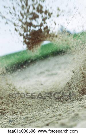 Stock Photograph - Sand flying in sand trap, close-up. Fotosearch