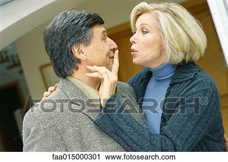 Senior couple, woman holding finger over man's mouth View Large Photo Image Stock Image - Senior couple, woman holding finger over man's mouth. Fotosearch