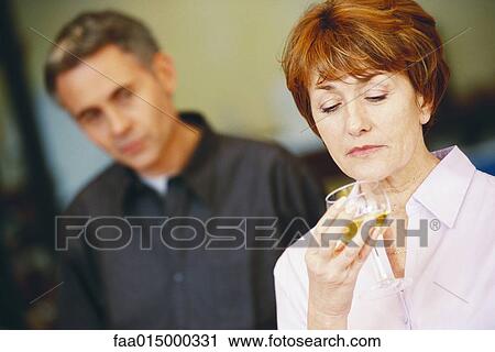 Senior woman with glass of wine, man looking at her in background View Large Photo Image Stock Image - Senior woman with glass of wine, man looking at her in background. Fotosearch
