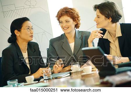 Stock Image - Three businesswoman sitting at table having meeting. Fotosearch