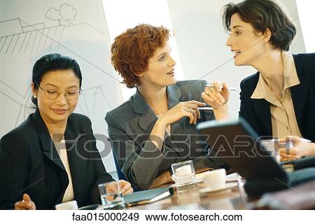 Stock Photo - Three businesswoman sitting at table having meeting. Fotosearch