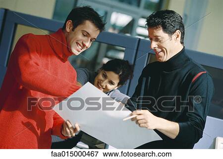 Three colleagues looking at document, smiling View Large Photo Image Stock Photo - Three colleagues looking at document, smiling. Fotosearch