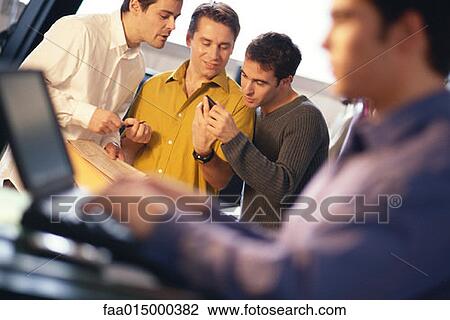 Three young men using electronic organizer, laptop user in foreground View Large Photo Image Stock Image - Three young men using electronic organizer, laptop user in foreground. Fotosearch