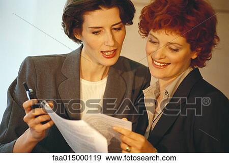 Two business women, looking at document View Large Photo Image Stock Photo - Two business women, looking at document. Fotosearch