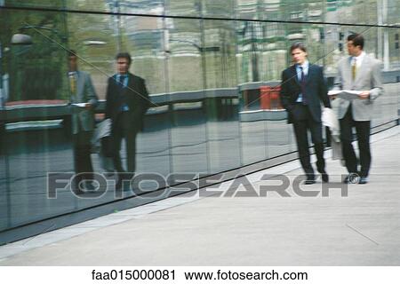 Two businessmen walking next to office building View Large Photo Image Stock Image - Two businessmen walking next to office building. Fotosearch