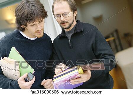 Two male colleagues looking at document View Large Photo Image Stock Photograph - Two male colleagues looking at document. Fotosearch