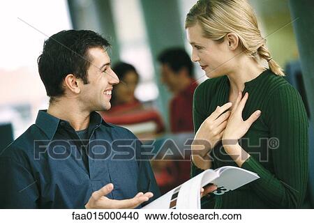 Woman gesturing to self, facing colleague holding brochure View Large Photo Image Stock Image - Woman gesturing to self, facing colleague holding brochure. Fotosearch
