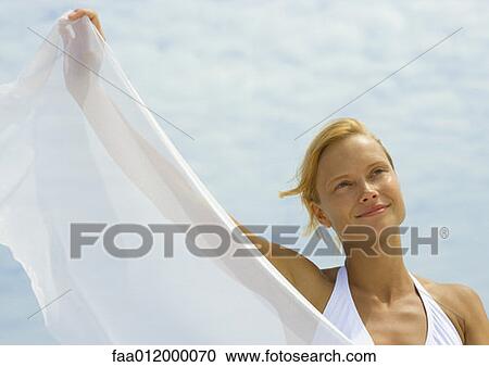 Woman holding up sheer cloth, smiling, sky in background View Large Photo Image Stock Image - Woman holding up sheer cloth, smiling, sky in background. Fotosearch