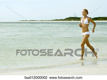 Woman in bikini running in surf at beach View Large Photo Image Stock Image - Woman in bikini running in surf at beach. Fotosearch