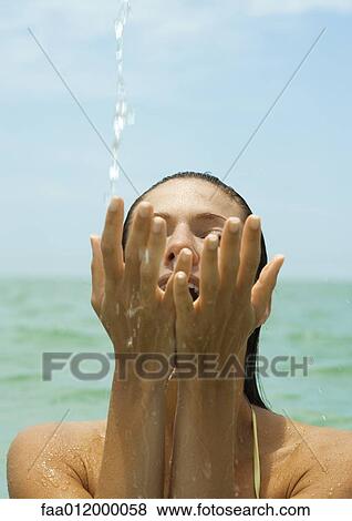 Stock Photo - Woman in sea, splashing water with hands, close-up. Fotosearch