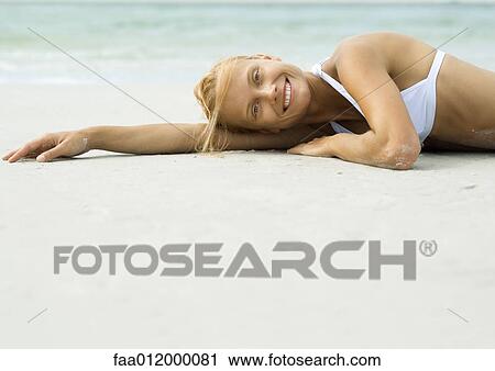 Woman lying on beach, smiling at camera View Large Photo Image Stock Image - Woman lying on beach, smiling at camera. Fotosearch