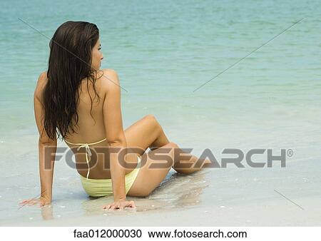 Woman sitting on sand with feet in surf, rear view View Large Photo Image Stock Image - Woman sitting on sand with feet in surf, rear view. Fotosearch