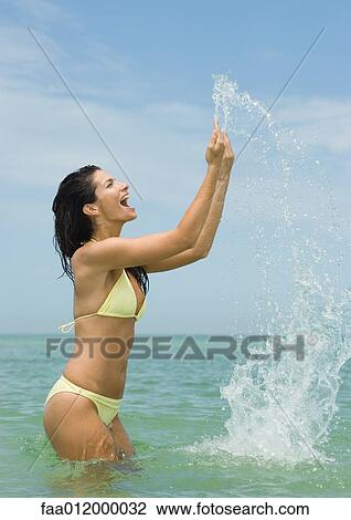 Woman standing in sea, splashing water with hands View Large Photo Image Stock Image - Woman standing in sea, splashing water with hands. Fotosearch
