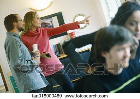Stock Photo - Woman standing next to man, pointing, in interior setting. Fotosearch