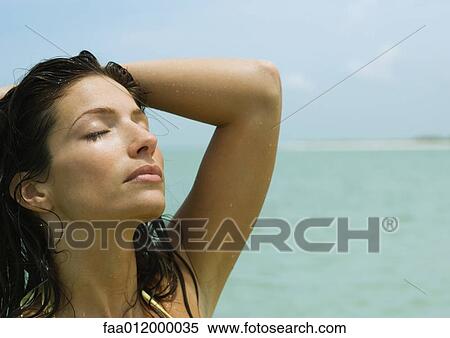 Woman with eyes closed and hand on head, sea in background View Large Photo Image Stock Photography - Woman with eyes closed and hand on head, sea in background. Fotosearch