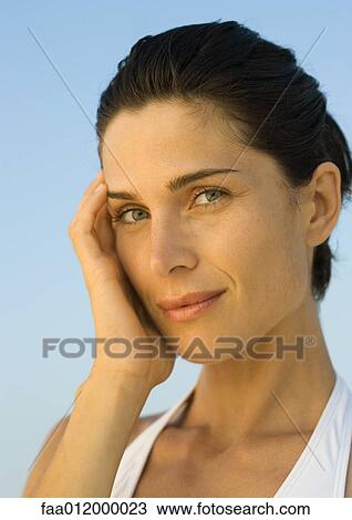 Stock Image - Woman with hand against cheek, portrait. Fotosearch